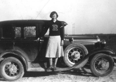 RRHS female student standing on floorboards of Model A in 1939 wearing letterman sweater