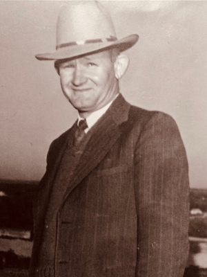 Superintendent O.F. Perry wearing a cowboy hat and suit standing on the top of Round Rock High School's roof.